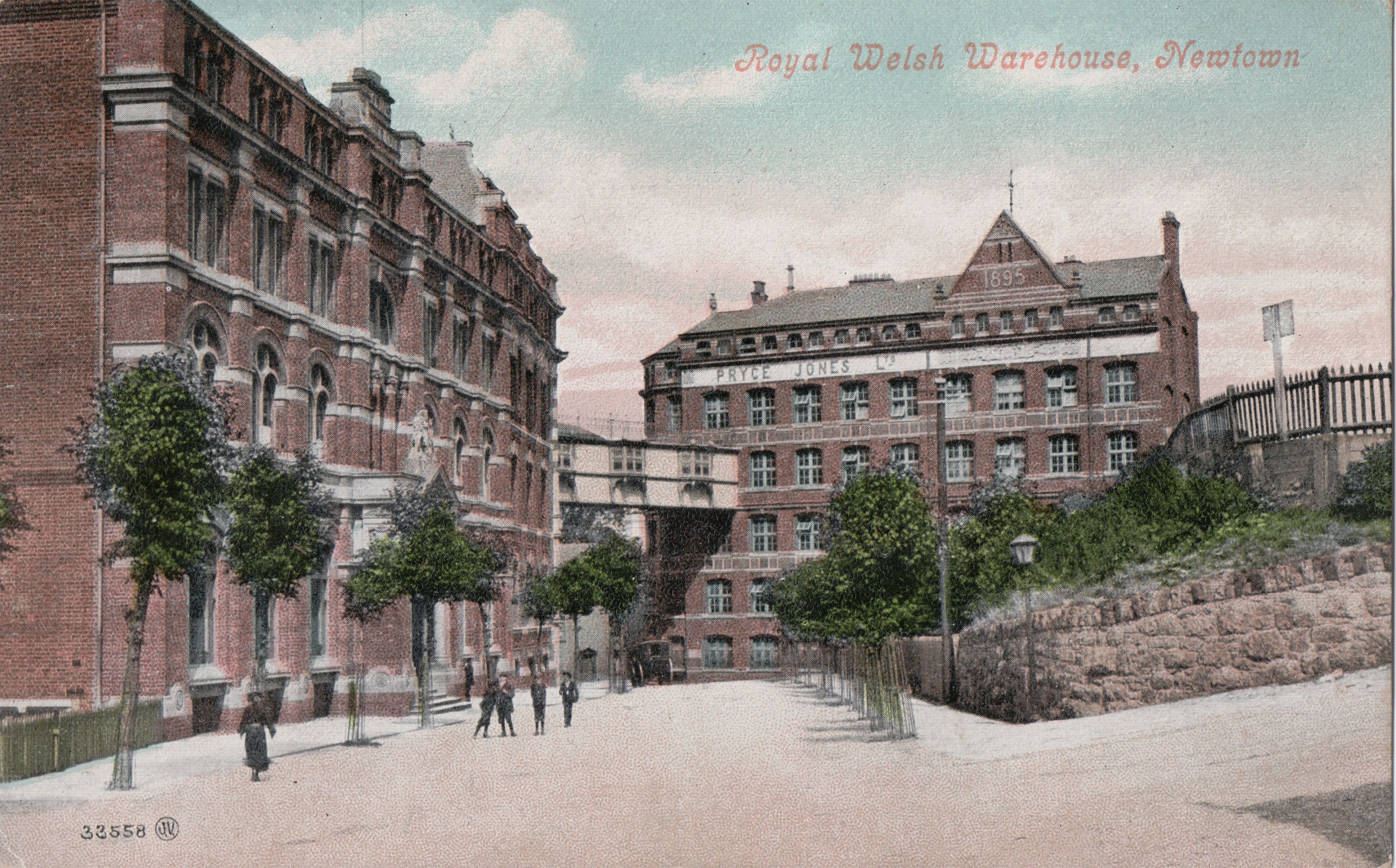 Early twentieth-century coloured postcard showing the Royal Welsh Warehouse, Newtown, with Pryce Jones Ltd displayed across the main warehouse building.