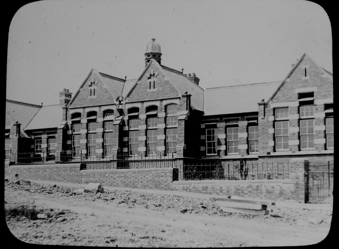 Early black-and-white photograph of Llandrindod Wells County School in Alexandra Road, showing its three gabled wings, tall classroom windows, railings and central roof cupola.